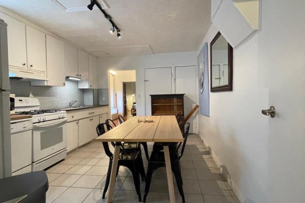 Kitchen and dining area with white cabinetry, wooden table, and stainless steel appliances. - 169 Gladstone Avenue, Toronto