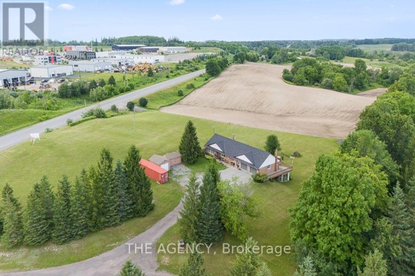 View of property from the forest edge, showing snow-covered land and nearby industrial area. - 169 Hwy 47, Uxbridge