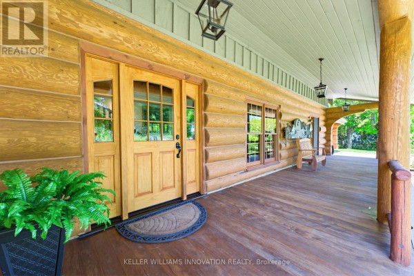 Covered wooden porch with double front doors, windows, and seating on the right. - 169 James Street, North Perth