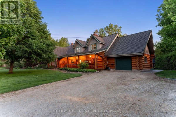 Log house with a garage, covered porch, and driveway under a twilight sky. - 169 James Street, North Perth