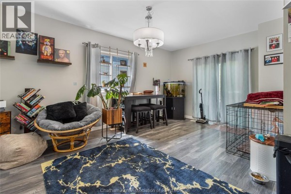 Papasan chair, dining table, fish tank, and dog crate in living room - 169 Lorne Avenue Chatham