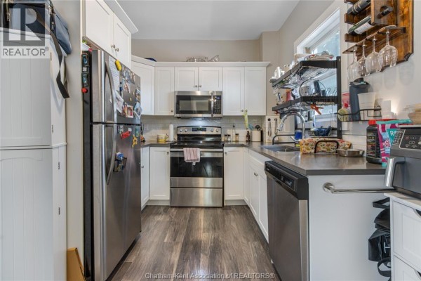 Modern kitchen with stainless steel appliances, white cabinets, and dark counters - 169 Lorne Avenue Chatham