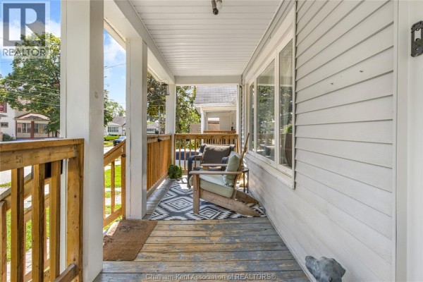 Covered porch with seating, rug, and dog statue - 169 Lorne Avenue Chatham