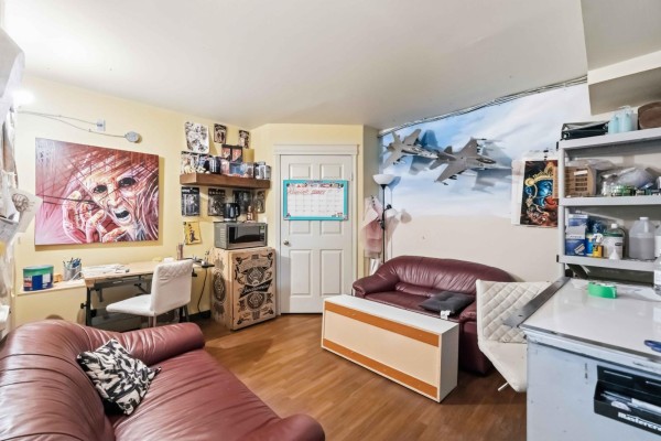 Room with leather couches, desk, microwave, and wall art including fighter jets. - 169 Marion St, Winnipeg