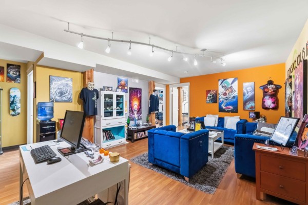 Spacious reception area with blue velvet furniture, desk, and artwork on orange walls. - 169 Marion St, Winnipeg