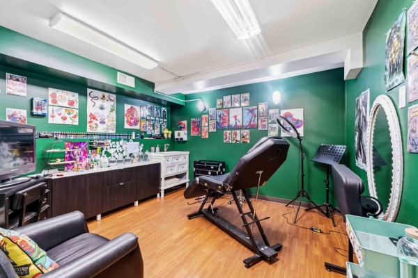 Tattoo studio with green walls, tattoo chair, desk, and sinks. - 169 Marion St, Winnipeg