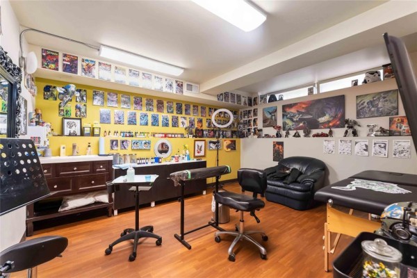 Tattoo studio interior with wooden floors, yellow walls, tattoo chairs, and wall art. - 169 Marion Street, Winnipeg