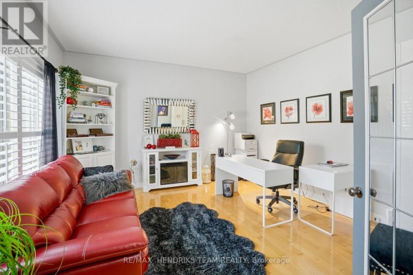Home office with a red leather sofa, white desk, chair, and a large white bookshelf. - 169 Michael Drive, Welland