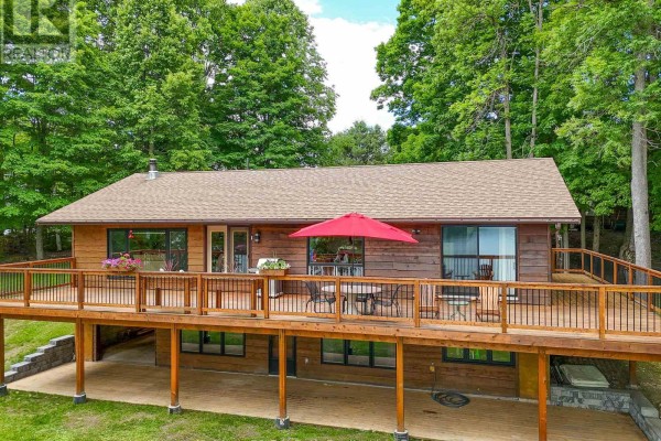 View of the house deck with outdoor furniture and a red umbrella. - 169 Odd's Drive, Parry Sound Remote Area