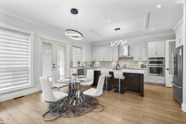 Open-concept kitchen and dining area with white cabinets, island, stainless steel appliances, and wood floors. - 1699* 18 Avenue, Surrey