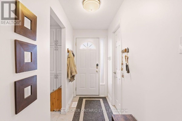 Bright white entryway with a glass-paneled door, coat rack, key holder, and wooden accents. - 1699e Lamoureux Drive, Ottawa