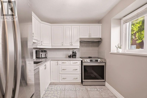 Compact kitchen with white cabinets, grey countertops, stainless steel appliances, and a tiled floor. - 1699e Lamoureux Drive, Ottawa