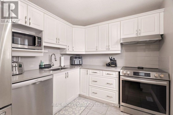 Kitchen with white cabinets, grey counters, stainless steel appliances including a microwave and dishwasher. - 1699e Lamoureux Drive, Ottawa