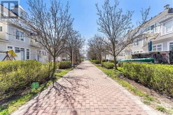 Paved pathway lined with trees leading to marina, with residential buildings on either side. - 17 - 1295 Wharf Street, Pickering
