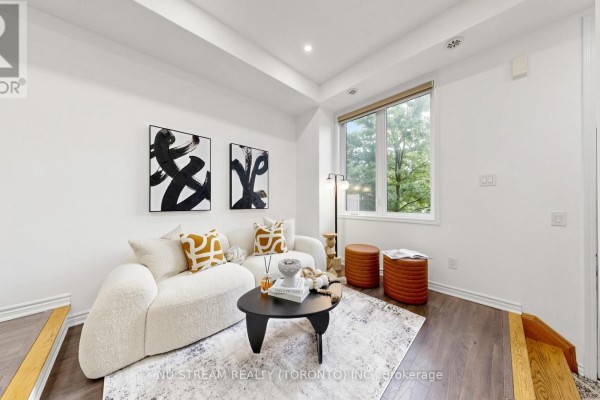 Living room featuring a white sofa, patterned rug, large window, and a floor lamp. - 17 - 15 Heron Park Place, Toronto