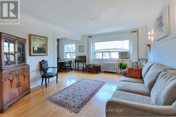 Living room with light wood floors, a sofa, rug, antique furniture, and a large window. - 17 - 1646 Bathurst Street, Toronto