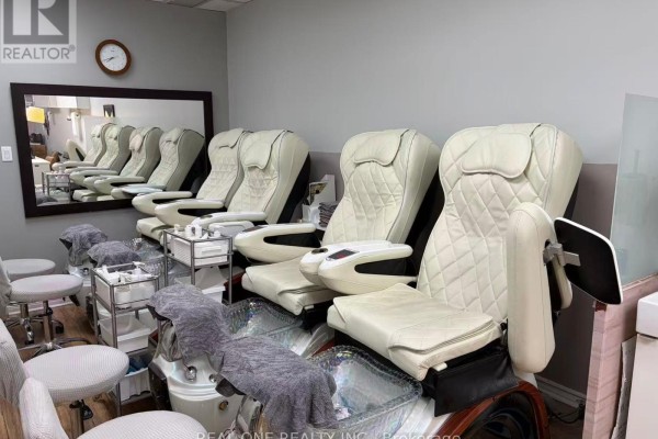 Row of white leather pedicure chairs with foot baths in the nail spa. - 17 - 3030 Don Mills Road, Toronto