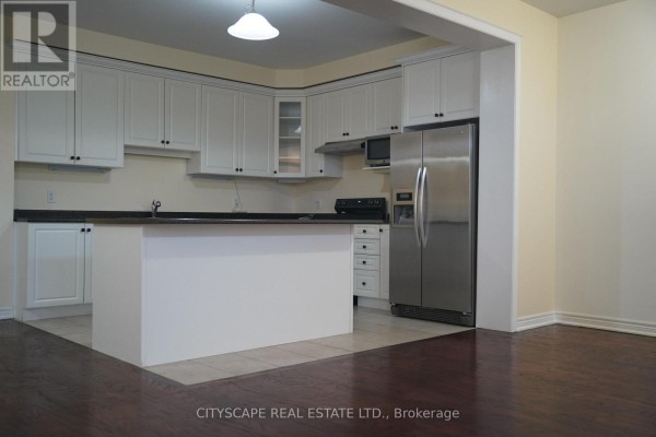 Kitchen with white cabinets, dark countertops, island, and stainless steel refrigerator. - 17 - 3045 Gladeside Avenue, Oakville