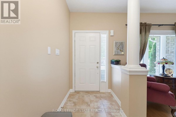 Interior front entryway with beige walls, tiled floor, and a white front door with a glass sidelight. - 17 - 310 Southbrook Drive, Hamilton