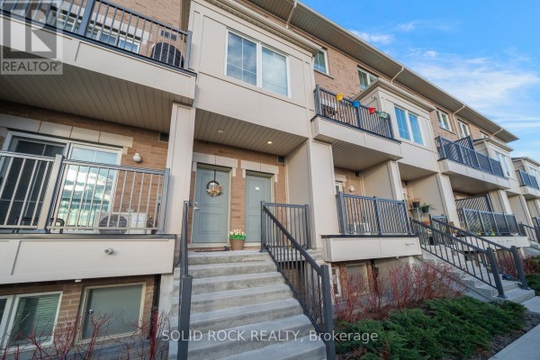 Front view of two townhouse entrances with stairs leading up to gray doors. - 17 - 480 Beresford Path, Oshawa