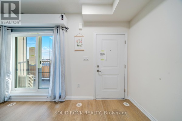 Interior room with a white door, large sliding glass door, and light wood flooring. - 17 - 480 Beresford Path, Oshawa