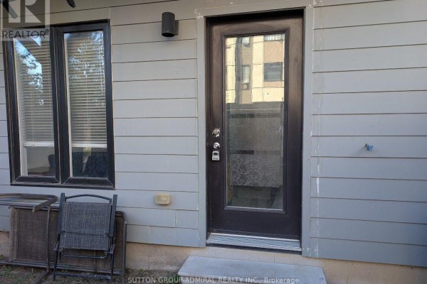 Back exterior of a grey house with a dark brown door and a window. - 17 - 540 Essa Road, Barrie