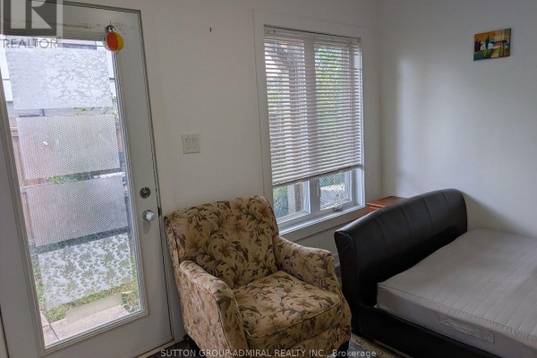 Small bedroom with a patterned armchair, a bed, and a window with blinds. - 17 - 540 Essa Road, Barrie
