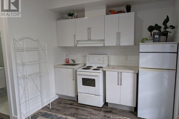 Compact kitchen with white cabinets, white appliances, and a dark wood floor. - 17 - 540 Essa Road, Barrie