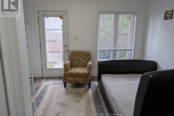 Bedroom with a door, a window, a bed, a patterned armchair, and a rug. - 17 - 540 Essa Road, Barrie