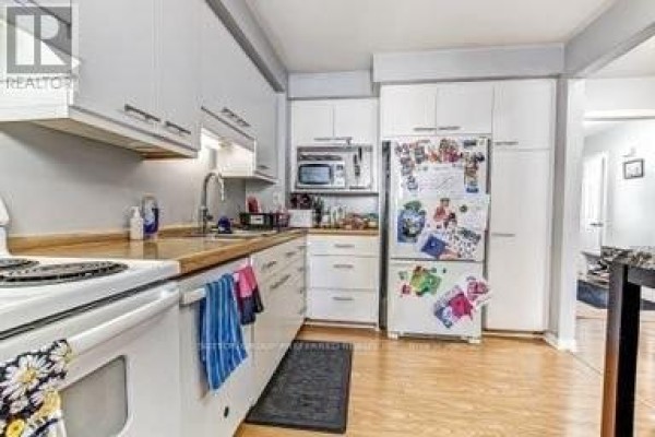 Galley kitchen with white cabinets, wood counters, and stainless steel microwave - 17 - 711 Osgoode Drive London South