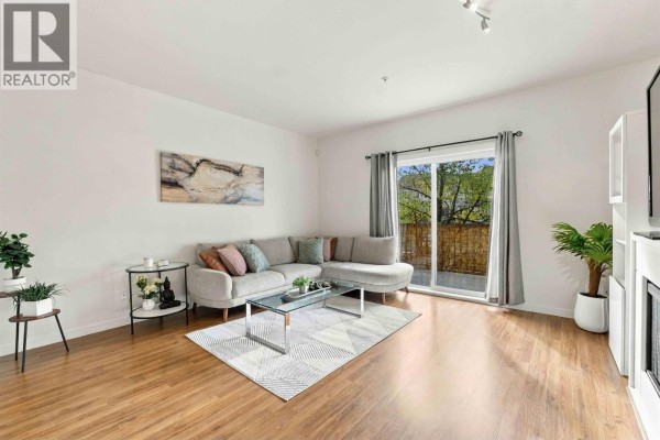Living room with sectional sofa, glass coffee table, rug, and sliding glass doors. - 17 19572 Fraser Way, Pitt Meadows