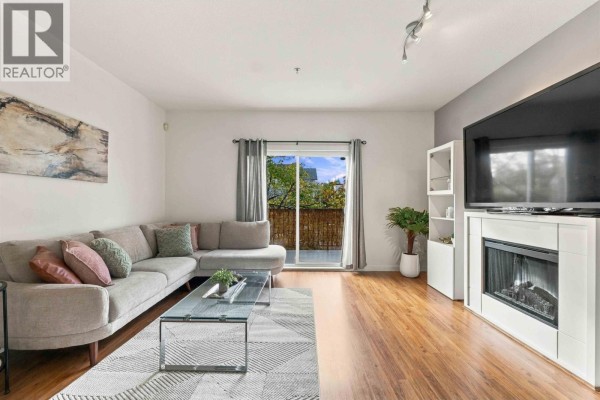 Living room with fireplace, television, sectional sofa, coffee table, and balcony access. - 17 19572 Fraser Way, Pitt Meadows