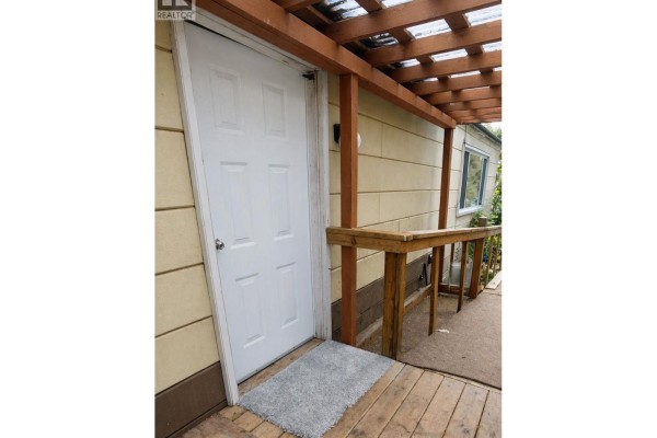 White front door of the mobile home with a wooden railing and pergola overhead. - 17 2123 Riverside Drive, Smithers