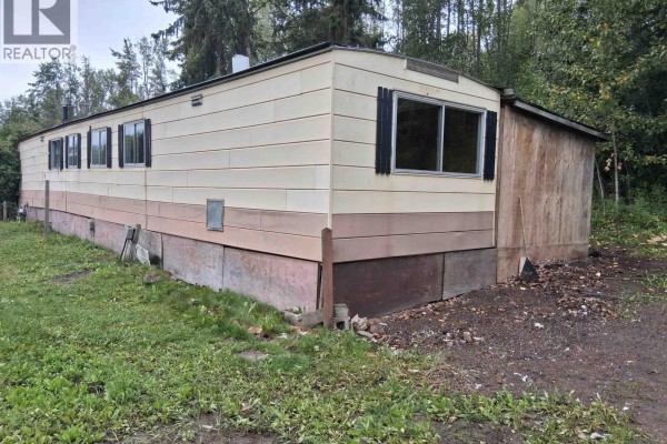 Back view of the beige and pink mobile home showing the skirting and exterior walls. - 17 2123 Riverside Drive, Smithers