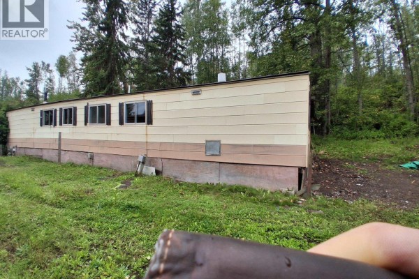 Side view of the mobile home with a grassy yard and trees in the background. - 17 2123 Riverside Drive, Smithers