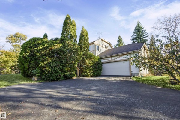 A house with a garage and driveway, surrounded by trees. - #17 26417 Twp Road 512, Rural Parkland County