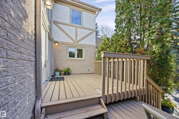 A wooden deck with stairs leading down to a driveway. - #17 26417 Twp Road 512, Rural Parkland County