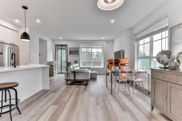Open concept living and dining area with a white kitchen island and light wood floors. - 17 8120 200a Street, Langley
