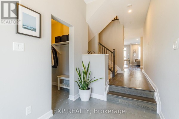Interior entryway with grey tile flooring, a bench, and dark wood stairs leading upstairs. - 17 Allan Moore Place, Ottawa