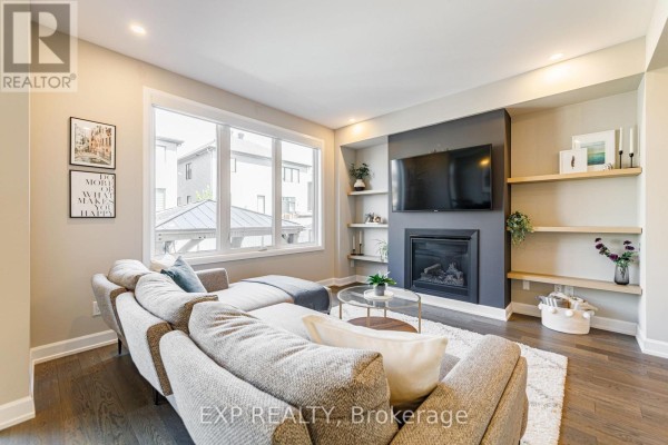 Living room with a sectional sofa, fireplace, television, built-in shelves, and large window. - 17 Allan Moore Place, Ottawa