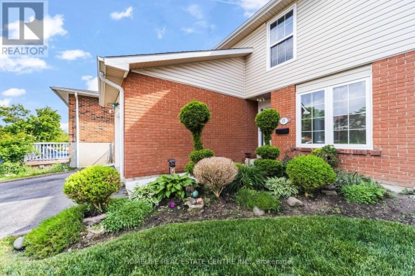 Close-up view of the front landscaping with manicured bushes and brick accents. - 17 Ashford Court, Brampton