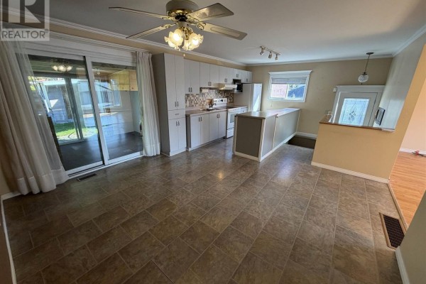 Open concept kitchen and dining area with light brown tile flooring and a large sliding glass door. - 17 Brown Rd, Elliot Lake