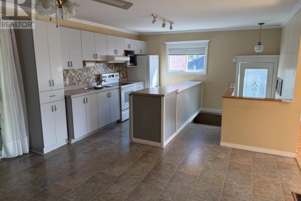 Kitchen with white cabinets, a central island, white appliances, and a decorative glass-paneled door. - 17 Brown Rd, Elliot Lake