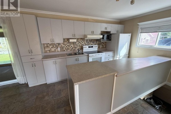 Kitchen with white cabinets and countertops, a white stove, refrigerator, and an island with a beige countertop. - 17 Brown Rd, Elliot Lake