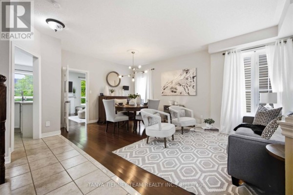 Open concept living and dining area with dark hardwood floors, beige walls, and modern furniture. - 17 Cody Avenue, Whitby