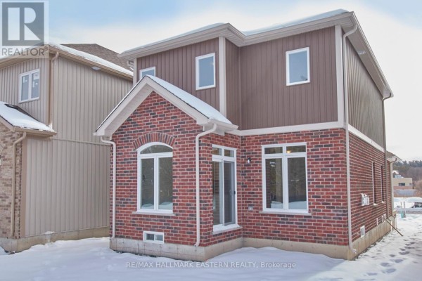 Rear exterior of a two-story brick and vinyl house with large windows and snow on the ground. - 17 Coldbrook Drive, Cavan Monaghan
