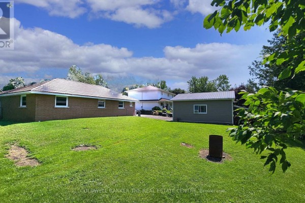 Rear view of brick bungalow and detached garage with large green lawn. - 17 Courtland Street, Ramara