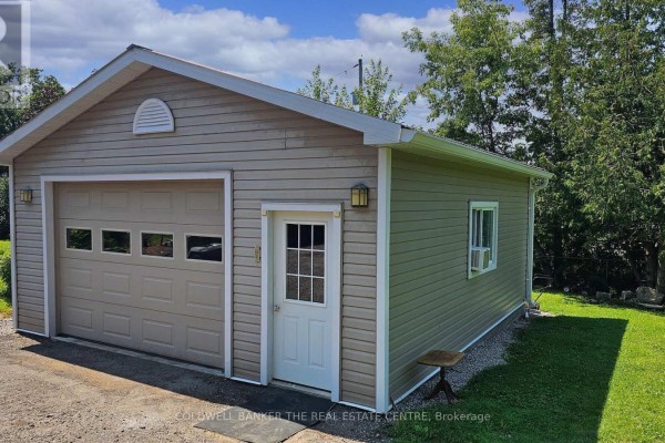 Exterior view of a beige siding detached garage with large door and window. - 17 Courtland Street, Ramara