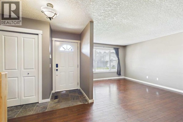 Entrance hallway with white doors and a view into the adjacent living room. - 17 Deermeade Road Se, Calgary