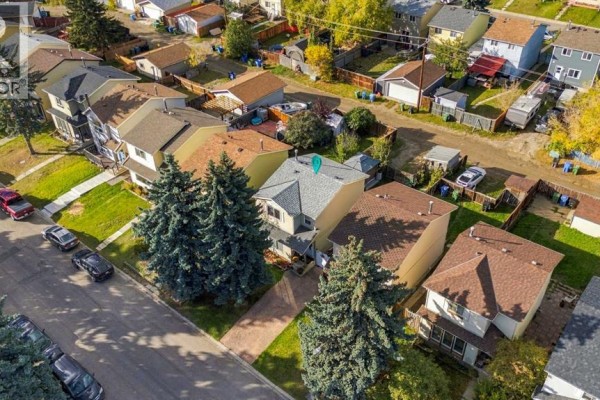 Aerial view of a residential street with houses, trees, and parked cars. - 17 Erin Ridge Road Se, Calgary